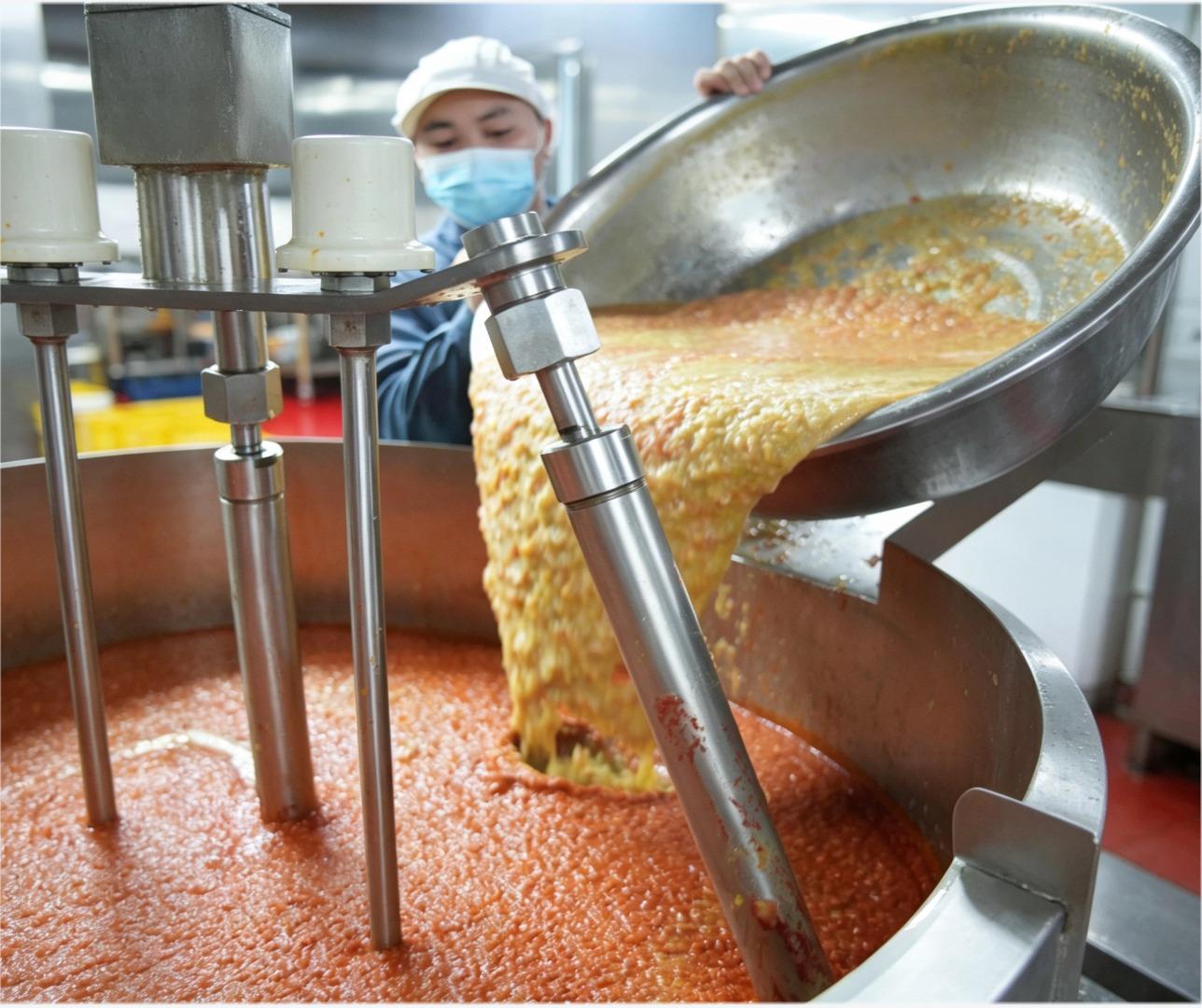 An operator transferring sauce into a production vessel at Seleglu