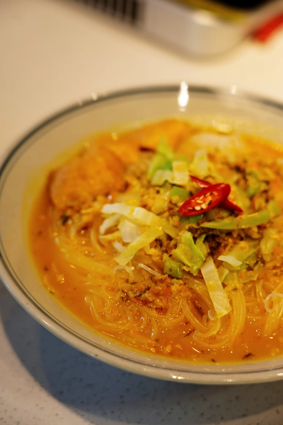 Glass noodles and vegetables in a bowl of golden broth