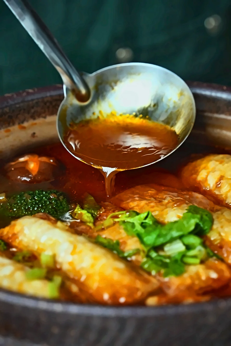 A ladle pouring sauce over food in a serving dish